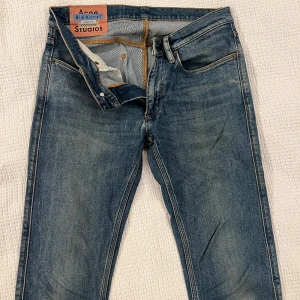 Acne Studios Blå Konst jeans blå - Snygga blå jeans från Acne Studios Blå Konst med klassisk femficksdesign och dragkedja. Jeansen har en rak passform och subtila slitningar för en avslappnad vibe. Tillverkade i robust denim av bomull. Perfekta för dig som gillar stilrena och tidlösa jeans.