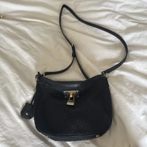Äkta dkny axelväska - Snygg svart axelväska från DKNY med justerbar rem och guldfärgade metalldetaljer. Nypriset ligget på 2000kr och kvaliteten ger en exklusiv känsla!❣️