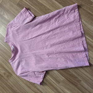 Ljusrosa t-shirt från Zara - Enkel och stilren ljusrosa t-shirt från Zara i mjuk bomull. Klassisk rund halsringning och korta ärmar. Perfekt för dig som gillar en clean och avslappnad look. Passar till allt och är superbekväm att bära hela dagen.