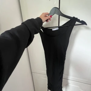 Svart tight kortklänning från DesignSian - Säljer en svart, tight och ärmlös kortklänning från DesignSian. Klänningen har en enkel och stilren design med rund halsringning och figurnära passform. Perfekt för dig som gillar minimalistisk stil och vill ha något som sitter snyggt.