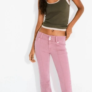 Bootcut jeans i rosa denim - Snygga rosa bootcut jeans med låg midja och raka sömmar framtill. Jeansen har klassisk femficksdesign, dubbla knappar i midjan och är tillverkade i mjuk bomullsdenim. Perfekta för dig som vill bryta av en svart eller vit blus med något fint och stilrent. Små i storlek