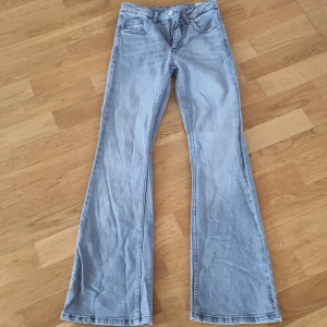 Ljusgrå bootcut jeans - Snygga ljusblå jeans med bootcut-stil. De har en klassisk femficksdesign och en knappgylf. Perfekta för en avslappnad look.