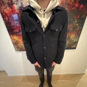 Mörk blå overshirt med knappar - Snygg mörk blå  overshirt med knappar framtill och två bröstfickor med lock. Perfekt för lager-på-lager-stil och passar bra till både hoodie och t-shirt. En stilren och mångsidig jacka för alla tillfällen. Perfekt nu till våren då de börjar bli lite varmare. Köpt från Oskar Jakobson för 3 300kr och är använd max 10 gånger. Kvitto och box ingår. Skriv vid fler frågor!