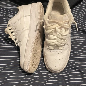 Nike Air Force 1 - Säljer ett par klassiska vita Nike Air Force sneakers. De har en stilren design med snörning och perforerade detaljer på ovansidan för ventilation. Perfekta för en casual look. Pris kan diskuteras vid köp! Tvättas även innan frakt!