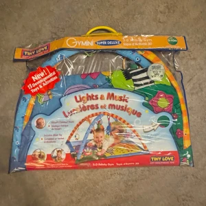 Säljer Tiny Love Gymini Super Deluxe Babygym – Nytt i Förpackning! - Säljer ett Tiny Love Gymini Super Deluxe babygym med ljus och musik. Perfekt för små barn (0-10 månader) med 15 utvecklande aktiviteter och leksaker. Fortfarande helt nytt i förpackningen!