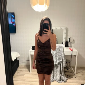 Brun tight klänning  - Snygg brun klänning med tight passform. Perfekt för en kväll ute. Klänningen har en kort längd och en elegant stil.