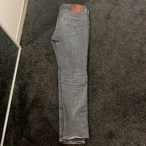 Grå jeansbyxor från Levis - Snygga grå jeansbyxor från Levis med klassisk femficksdesign och en läderpatch baktill. Perfekta för en stilren look.