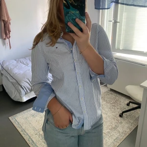 Tommy Hilfiger skjorta - Säljer en stilren blå och vit randig skjorta från Tommy Hilfiger. Perfekt för en avslappnad men ändå uppklädd look. Använd men i bra skick✨