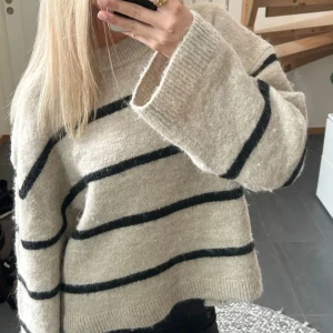 Stickad tröja - Stickad tröja i beige, med svarta ränder. Jätte bekväm! Köpt på Gina för 399kr. Lånad bild, skriv för fler bilder!
