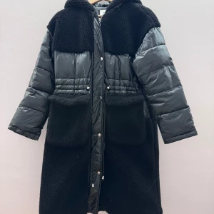 Svart pufferjacka med teddyfoder - Säljer en svart pufferjacka med teddyfoder och huva. Jackan har långa ärmar och stängs med knappar. Perfekt för kyliga dagar med sin kombination av puffer och teddy för extra värme. är som helt ny dock så kan dragkedjan krångla lite ibland men det ska nog inte vara några problem!