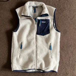 fleeceväst från Patagonia - Säljer en snygg vit fleeceväst från Patagonia. Toppskick helt ny! Perfekt för lager-på-lager under kyliga dagar. Tveka inte vid funderingar!