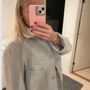 Grå kappa med knappar - Grå vår/höstjacka. Väldigt fint skick nästintill nyskick! Storlek M men passar på mig som normalt har S och är 175cm