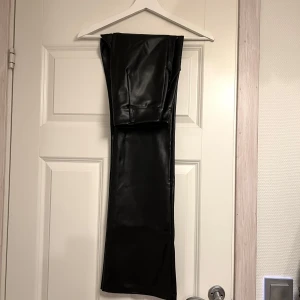 Svarta skinnbyxor från Madlady - Snygga svarta skinnbyxor från Madlady i storlek S. Byxorna har en högmidjad design och bootcut. Perfekta för en stilren look med en knappdetalj vid midjan.