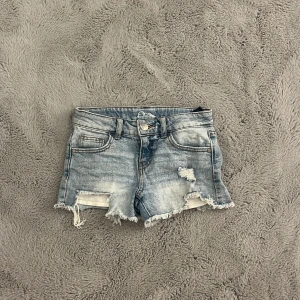 Blå jeansshorts från Target (i usa) - Säljer ett par ljusblåa jeansshorts med slitningar längs nere💞Jag köpte dom på Target i USA 2023 så de är inte från något speciellt märke🫶🏻De är i storlek M för barn så storlek XXS för vuxna🫶🏻 De är i mycket bra skick för jag har använt de ett få antal gånger🤗De är väldigt lågmidjade och snygg färg😍De går även att spänna i midjan, skriv om ni undrar något mått eller så🥰