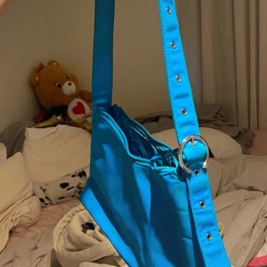 Blå axelväska med dragkedja - Snygg blå axelväska med justerbar rem och dragkedja. Lite fläckar (se bilder) men inget som syns super mycket. 