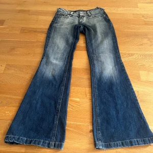 Blå bootcut jeans - Blå urtvättade bootcut jeans med snygga bakfickor!💘Uppklippta it midjan och slitningar längst ner. Midjemått rakt över: 38 Innerbenslängd: 80. 