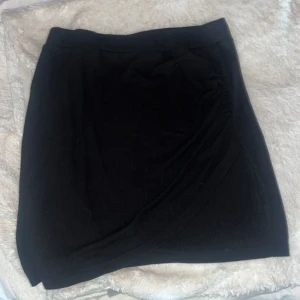 Svart kjol - Snygg ribbad kort svart kjol med slits. 