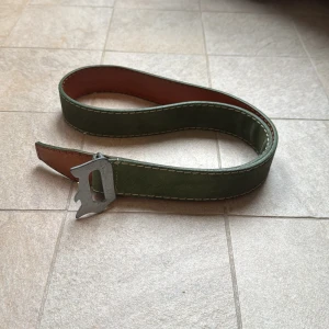 Dondup mocka bälte  - Säljer ett schysst Dondup bälte med  grön mocka/äkta läder på povansida och brun undersida. Bältet har ett unikt metallspänne med Dondup ”D”. Kostar runt 1700kr nytt, det är i superbra skick-finns två stygn på insidan som lossnat lite, men går att laga me enkel nål o tråd för hand. Storlek ser ni på bilden🙌🏼