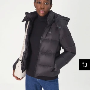 Svart dunjacka från Calvin Klein - Snygg svart dunjacka från Calvin Klein med dragkedja och huva. Jackan har en pufferdesign och är perfekt för kyligare väder änvänt minst en månad inte min still längre