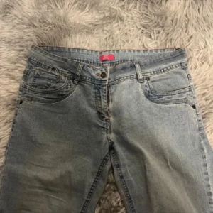 Blå jeans med broderade bakfickor - Snygga blå jeans med unika broderade detaljer på bakfickorna. De har en klassisk femficksdesign och en knappgylf. Perfekta för en avslappnad stil.