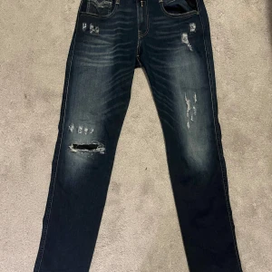 Replay Anbass jeans - Snygga Replay Anbass jeans i mörkblå denim med slitna detaljer. De har en slim fit passform storlek W29 L32 och är tillverkade i ett stretchigt material för extra komfort. Perfekta för en trendig look. Den är slutsålt i Sverige vad jag sätt så extra Limited! Hör av er för mer detaljer!💌