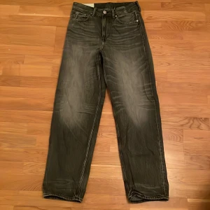 Mörkgråa H&M jeans med ljusare betoning vid låren - Snygga mörkgrå jeans med en cool tvättad look. Jeansen är från H&M och är knappt använda.     De har en lös passform och klassisk femficksdesign. Storleken är W28 L32.      Perfekta för den som gillar lösare kläder.                     Skriv vid minsta fråga. Är öppen för prissänkning.