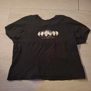 Svart t-shirt med månfastryck - Säljer en svart t-shirt från Divided med ett coolt månfastryck på framsidan. T-shirten har korta ärmar och en normal passform. Perfekt för en avslappnad stil. Pris kan diskuteras