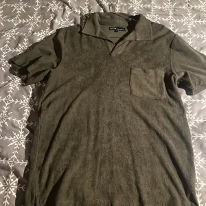 Olivgrön kortärmad t-shirt från SCW - Snygg olivgrön t-shirt från SCW med krage och en bröstficka. Perfekt för en avslappnad stil. T-shirten har en mjuk känsla och är kortärmad.