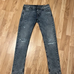 Grå jeans med slitningar - Snygga grå jeans med slitningar för en trendig look. De har en klassisk femficksdesign och en knappgylf. Perfekta för en avslappnad stil.