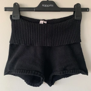 Svarta stickade shorts från Nelly - Säljer svarta lågmidjade shorts från Nelly som är stickade och har nedvikbar midja. Använda få gånger 🤍 obs det är damm på shortsen, inte nopper. 