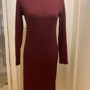 Vinröd ribbad klänning M - Snygg vinröd klänning med ribbad struktur och långärmad design. Perfekt för kyligare dagar med sin stilrena och enkla look. Klänningen har en tight passform som framhäver figuren. Lång klänning  Längd: 105 cm Armhåla till armhåla: 45 cm  Inga bilder när den sitter på mig!