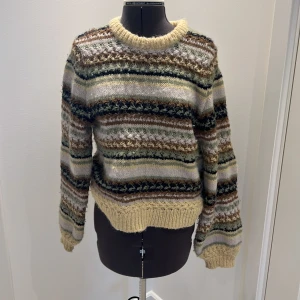 Mönstrad stickad tröja från ONLY - Säljer en mysig stickad tröja från ONLY i storlek XS. Tröjan har ett färgglatt mönster i beige, brun, grön och vit med långa utsvängda ärmar och rund hals. Perfekt för kyliga dagar!💚🤎💛🤍