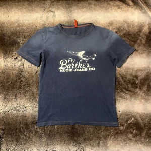 Nudie Jeans Co T-shirt - Säljer denna blåa t-shirt från Nudie Jeans Co med ett diskret tryck på framsidan som bidrar till en avslappnad stil. Skriv om ni undrar något!