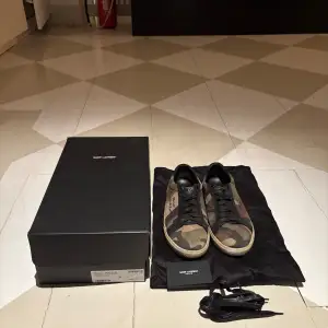 Snygga sneakers från Saint Laurent i ett coolt camouflage-mönster. Skorna har svart snörning och en klassisk design med märkets logga på sidan. Perfekta för en avslappnad stil med en touch av lyx.