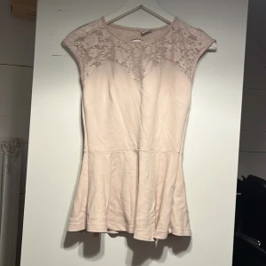 Ljusrosa  tröja/topp Gina Tricot - Supersöt ljusrosa tröja/topp från Gina Tricot i storlek S. Tröjan har spets upptill med blommigt mönster och en liten öppning i ryggen. Längst ner på toppen/tröjan är lätt utsvängd och materialet känns mjukt och bekvämt. Perfekt för dig som gillar romantisk stil!