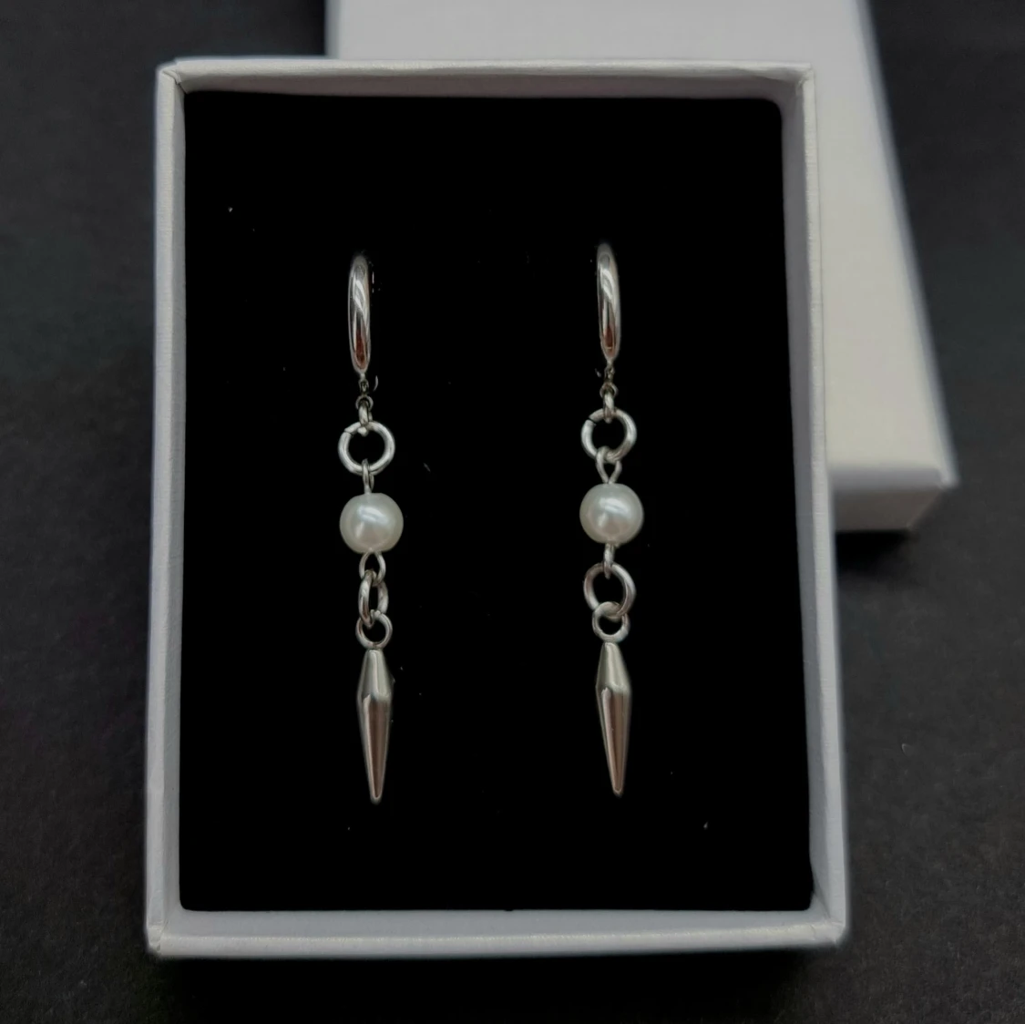 Silvriga örhängen med pärldetalj