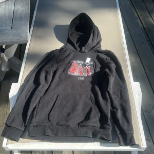 Svart hoodie Throwback NBA 1995 - Svart hoodie från Throwback med stor huva och magficka. Framsidan har tryck med basketspelare och texten 'One for all, all one 1995'. Baksidan har ett längre vitt tryck med text om NBA och Chicago Bulls. Perfekt för dig som gillar sport och streetwear. Ny pris är 890kr. det är S men är väldigt lång