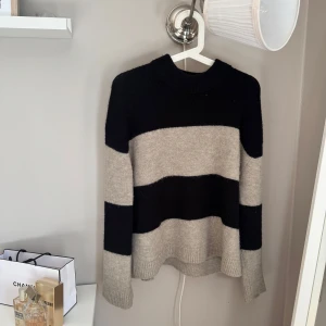 Randig stickad tröja - Snygg stickad tröja från Gina Tricot i storlek XS. Tröjan har breda svarta och beige ränder, rund hals och långa ärmar. Perfekt för dig som gillar en chill och trendig look med lite oversized känsla. Mjuk och skön kvalitet som håller dig varm. Sparsamt använd 