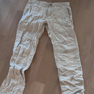 Beiga linnebyxor från Kappahl W30 L32 - Snygga beiga linnebyxor från Kappahl i storlek W30 L32. Byxorna har klassisk rak passform, sidfickor och en bakficka med knapp. Perfekta för varma dagar med sitt svala linnematerial och stilrena look.