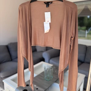 Bolerotopp  - Snygg croppad bolerotopp från H&M i en varm brun nyans. Tunn och mjuk, med långa ärmar och öppen framtill. 