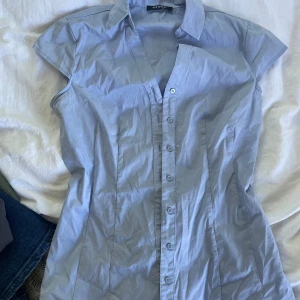 Ljusblå kortärmad skjorta från Orsay - Snygg ljusblå skjorta från Orsay med klassisk krage och knappar hela vägen framtill. Skjortan har korta ärmar och figurnära passform. Står ingen storlek men skulle säga s/xs💞