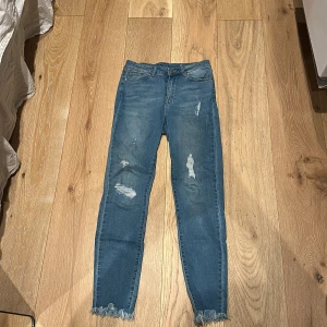 Blå skinny jeans från Vila med slitningar - Säljer ett par blå skinny jeans från Vila med snygga slitningar och fransade benslut. Jeansen har klassisk femficksdesign, normal passform och är tillverkade i stretchigt jeansmaterial. 