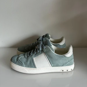 Valentino flycrew skor - Ett par väldigt snygga och eftertraktade valentino flycrew skor i en grå/turkos färg. De är i storleken 40,5. Vidare är skorna i ett väldigt bra skick, förutom att 6 nitar lossnat. Inga tillbehör är inkluderade. Skriv gärna vid funderingar!