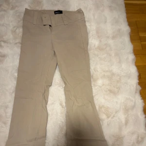 Beige bootcut byxor från Gina Tricot - Snygga beige bootcut-byxor från Gina Tricot i storlek 34. Byxorna har bred linning med hällor och klassisk dragkedja framtill. Tillverkade i mjukt bomullsmaterial som är skönt mot huden. Perfekt för dig som gillar en stilren och enkel look. Helt slutsålda OBS dem är endast skrynkliga då jag nyligen har flyttat o packat upp dem annars i jätte bra skick❤️
