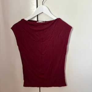 Vinröd topp från 157, XS - Snygg vinröd topp från 157 i mjuk bomull. Modellen är ärmlös med bredare axlar och har en enkel, rak passform som sitter skönt mot kroppen. Aldrig använd