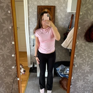 Ljusrosa topp - Säljer en ljusrosa topp med korta ärmar och ribbad struktur på ena sudan som ger en cool, rynkad effekt.