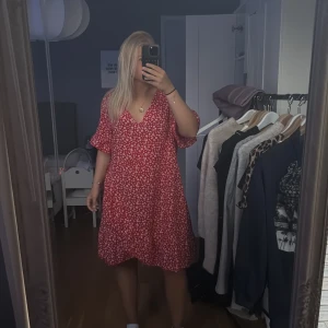 Röd blommig klänning  - Superfin röd klänning från SHEIN med vita blommor, v-ringad hals och korta, lite fladdriga ärmar. 