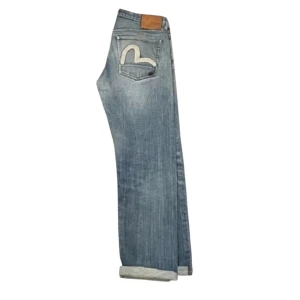 EVISU SELVEDGE DENIM - Ett par sjukt goa Evisu selvedge jeans! Vävda i Japan och är 100% bomull. Priset är pga byxorna är i hyfsat skick (se alla bilder) några fläckar som inte går bort samt lite heelbite som jag inte fick med på bilderna. Utöver det så har jeansen mycket liv kvar och är perfekt för dig som vill sticka ut men endå inte för mycket!! W32 och skulle gissa på L32. Mått finns ifall du vill ha dem! Om du har frågor så är det bara att säga till🤩