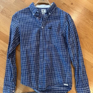 Blårutig skjorta från Lee, stl S - Snygg blårutig skjorta från Lee i regular fit. Skjortan har klassisk krage, knappar framtill och en bröstficka med Lee-logga. Tillverkad i mjuk bomull, perfekt för dig som gillar avslappnad stil med lite edge.