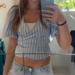  omlottopp - Superfin omlottopp med blå och vita ränder och puffiga korta ärmar. Köpt från Gina! Skriv för frågor eller fler bilder💞